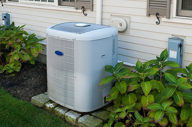 5 Questions to Ask Your HVAC Contractor. Photo of a white HVAC unit installed outside of a home.